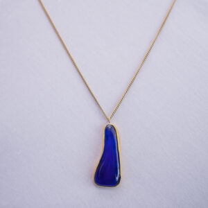Deep ocean blue glass set in water drop form dangling on an elegant slim brass chain