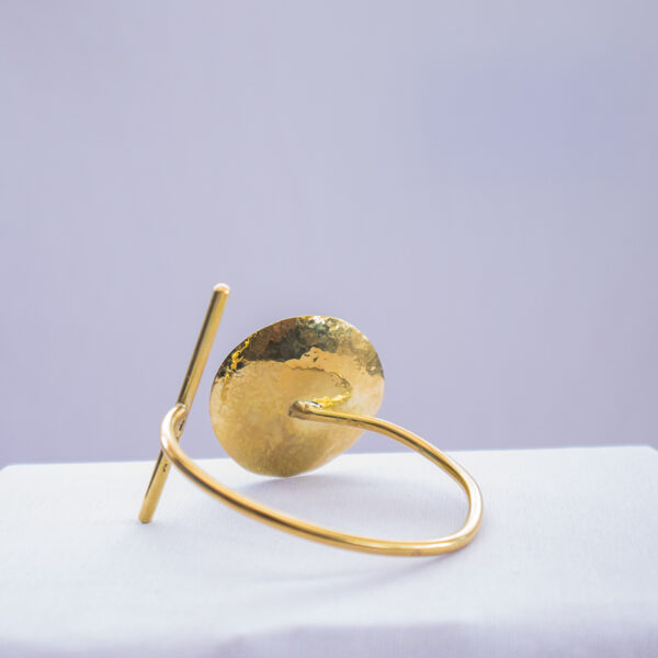 Kenyan-made brass bracelet with concave design and adjustable wrist band.