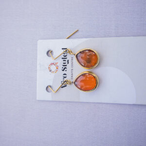 Dangling brass earrings with orange beads made from recycled glass.