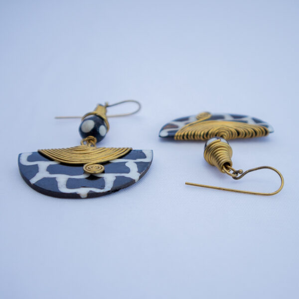 Unique pair of handcrafted dangling earrings. Made from bone with a black and white giraffe pattern and delicate brass wire detail.