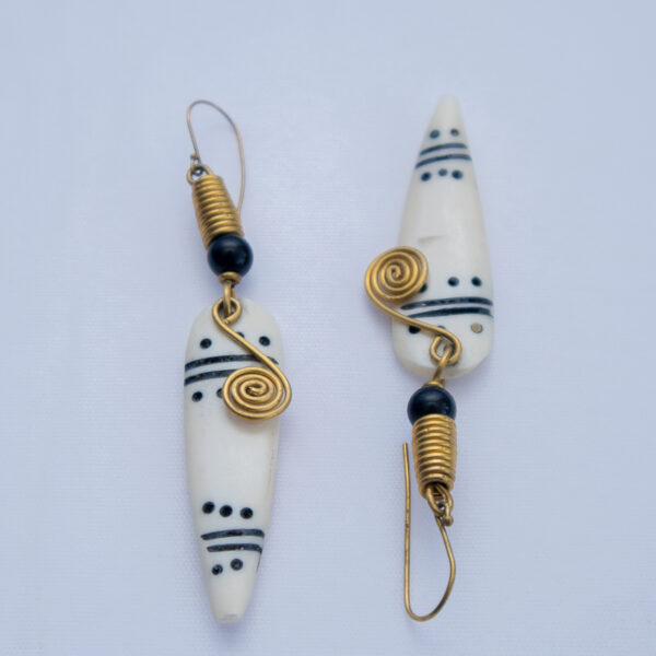 Unique pair of handcrafted dangling earrings. Made from bone with a black and white giraffe pattern and delicate brass wire detail.