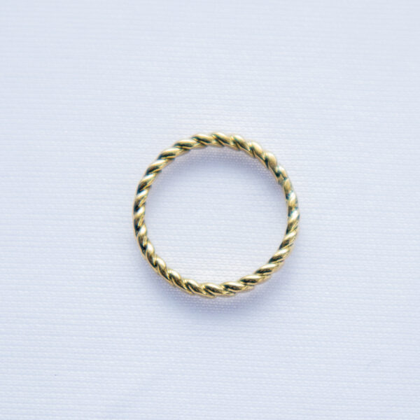 Minimalistic brass ring with rope-like twisted design and a smooth texture.