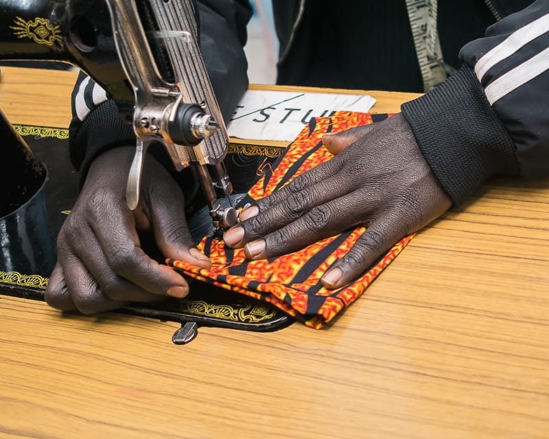 A young woman focused on sewing colorful fabric for Afrostyled packaging bags at Beyond Fistula Eldoret