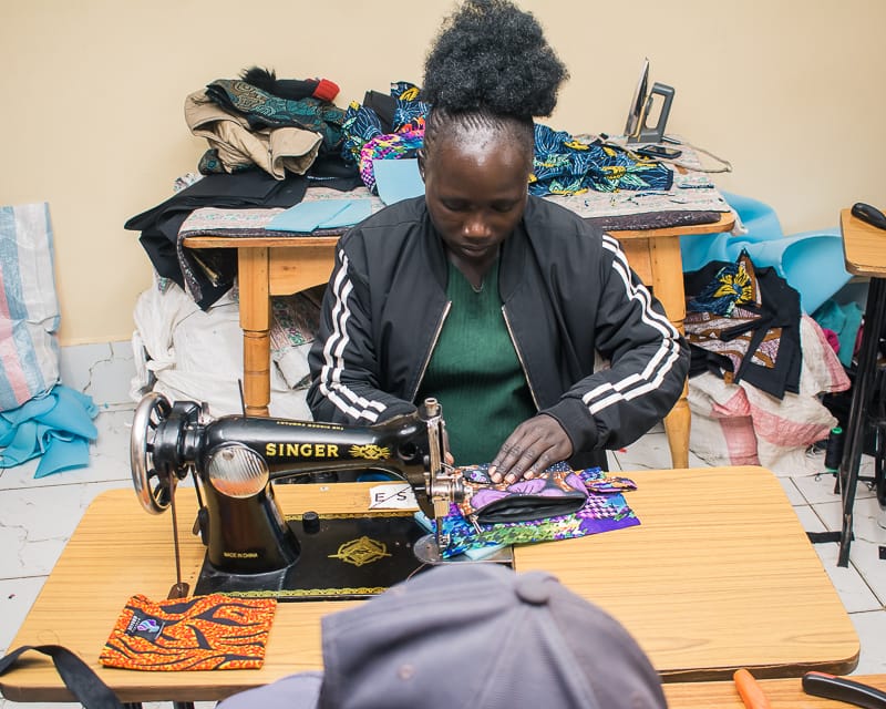 A young woman focused on sewing colorful fabric for Afrostyled packaging bags at Beyond Fistula Eldoret