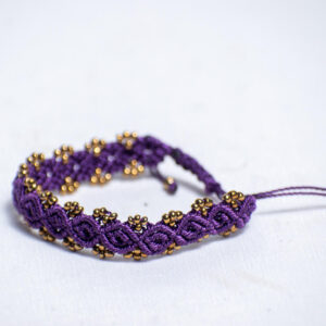 Handwoven purple cord bracelet with shiny gold-like beads and adjustable closure.
