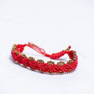 Handwoven red cord bracelet with shiny gold-like beads and adjustable closure.