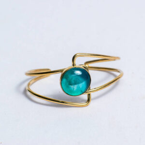 Handcrafted brass bracelet featuring a vibrant recycled blue glass design at the center.