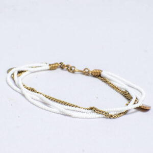 White beaded anklet with a brass chain link and a heart-shaped brass love charm.