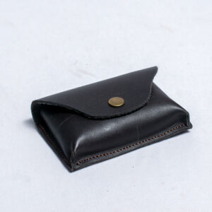 Small dark leather pouch with snap button closure and visible stitching.