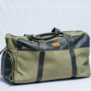 Heavy duty green canvas travel bag with black leather handles featuring a side shoe compartment allowing you to store shoes separately for better organization,handcrafted in Kenya.