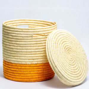 Cylindrical woven basket with lid featuring featuring spiral pattern in beige,orange and natural tones.