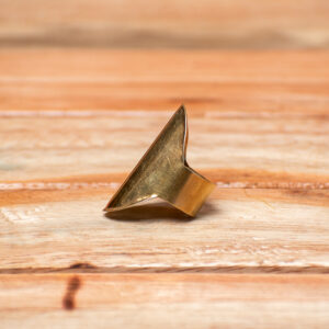 A handcrafted gold-tone brass statement ring featuring a dramatic, elongated shield silhouette with a sharp, raised central crest.