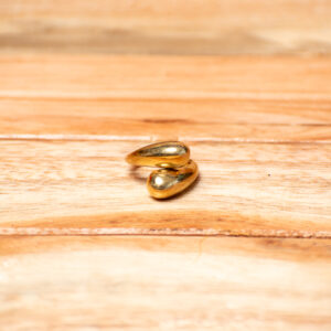 A gold-tone brass bypass ring featuring a polished, wrap-around band that ends in two smooth, overlapping teardrop-shaped accents.