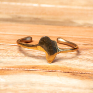 A handcrafted golden brass open-ended cuff bracelet, featuring a smooth, polished metallic band centered with a solid cutout shape of the African continent.