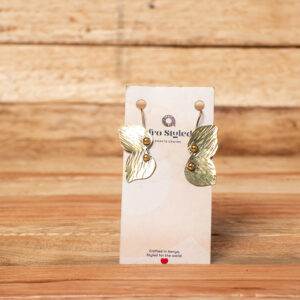 A pair of handcrafted golden brass drop earrings shaped like abstract butterflies with textured, etched wings and small, raised metallic beads along the center body.