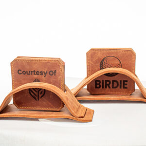 Brown handcrafted leather coaster set with matching holder, featuring engraved custom branding and fine stitching.