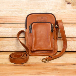 A small tan leather crossbody pouch with a front zipped pocket and long shoulder strap.