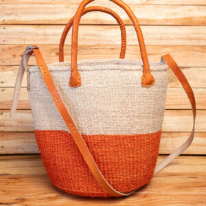 A two-tone orange and natural cream woven sisal tote bag with brown leather handles and a long adjustable shoulder strap.