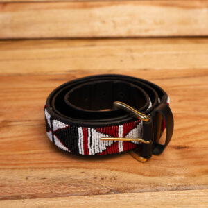 A coiled black leather belt fully hand-beaded with a red, white, and black geometric pattern and finished with a brass single-prong buckle.