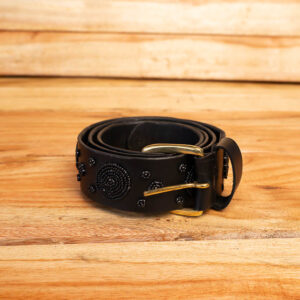 A coiled black leather belt decorated with black beaded circular spiral motifs and finished with a brass single-prong buckle.