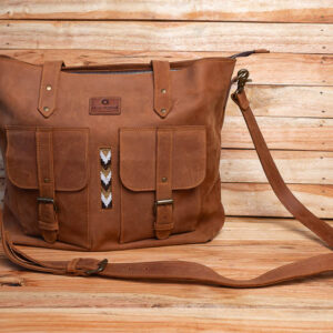 A tan brown leather messenger tote bag featuring two buckle front pockets, subtle vertical beadwork detail, and an adjustable shoulder strap.