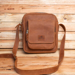 A compact tan brown leather crossbody messenger bag featuring a front flap pocket and an adjustable shoulder strap.