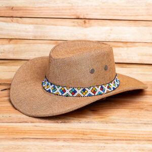 A tan woven straw cowboy hat featuring an upturned brim, metal ventilation eyelets, and a colorful geometric-patterned beaded band.