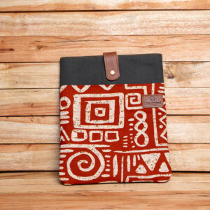 A padded laptop sleeve featuring rust-red African geometric print fabric, dark green canvas trim, and a brown leather snap closure strap.