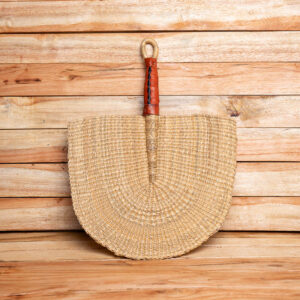 A natural tan handwoven straw hand fan with a brown leather-wrapped handle and a woven hanging loop at the top.
