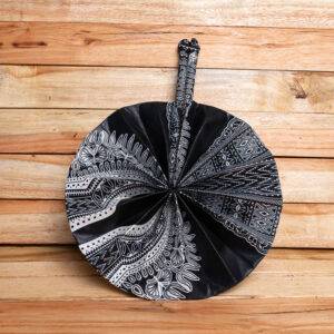 A circular folding hand fan made of black and white printed African fabric with matching fabric handles and a top loop