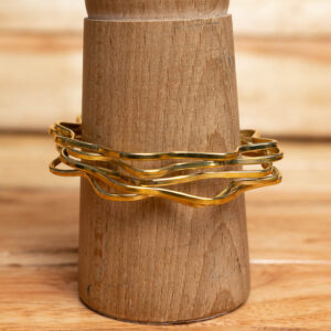 A set of stacked gold-tone wavy brass bangles with a high-polish finish.