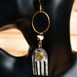 A horn drop earring featuring a brass hoop, a patterned batik bead, and a carved horn pendant with vertical cutouts and a spiral wire design.