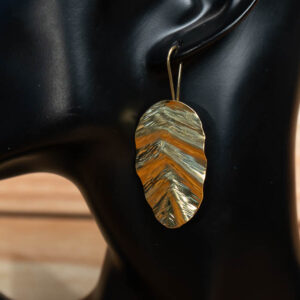 A gold-tone brass leaf drop earrings with a rippled, textured surface that reflects the light.
