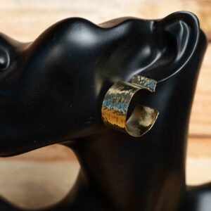 A wide, hammered brass open hoop earring with a rich hammered texture.