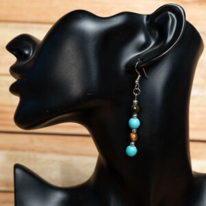 A vertical beaded drop earring with turquoise and tiger's eye beads separated by silver spacers, displayed on a black mannequin.