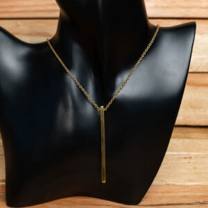 A gold-tone brass necklace with a sleek vertical bar pendant displayed on a black mannequin stand.