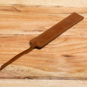 A slim tan leather bookmark with yellow edge stitching and a leather tassel.